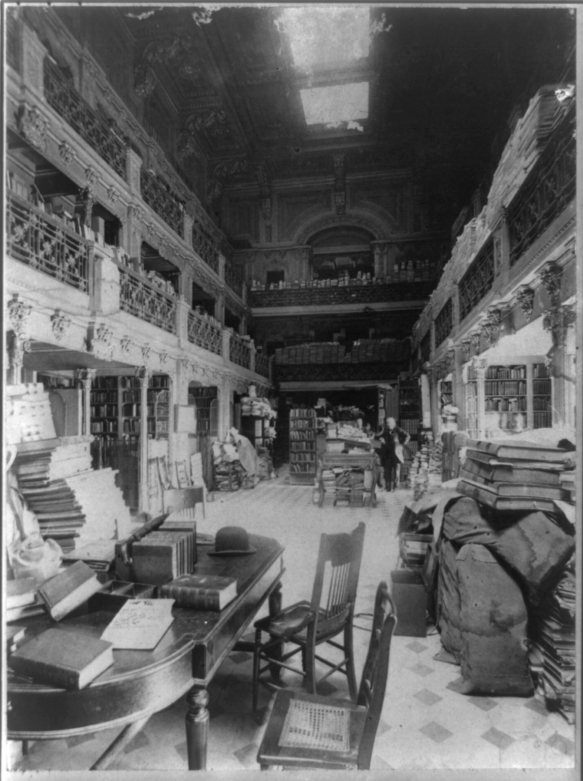 Library stacks crowded floor to ceiling with books, bundles and newspapers